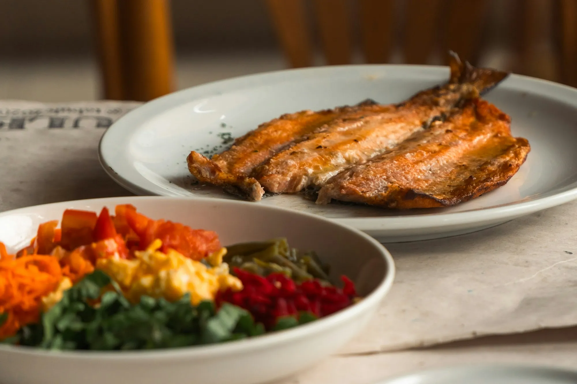Prato de peixe grelhado ao lado de uma salada colorida